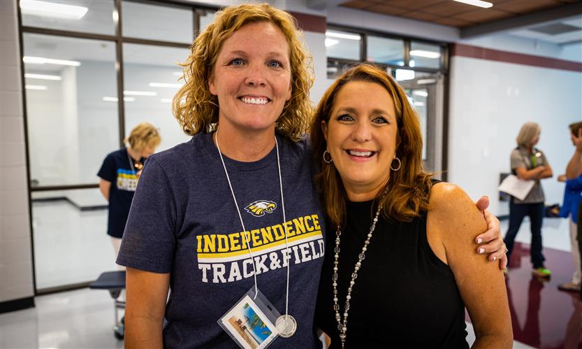 Two administrators stand together and smile